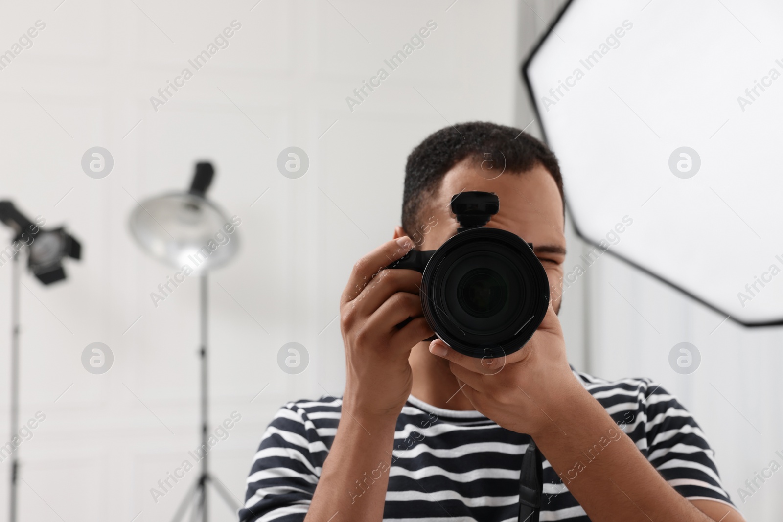 Photo of Professional photographer taking picture in modern photo studio, space for text