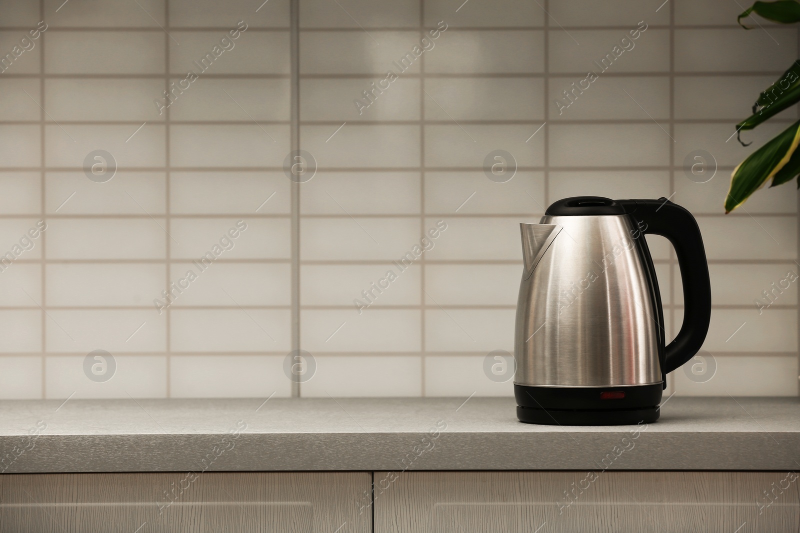 Photo of Modern electric kettle on grey kitchen counter. Space for text