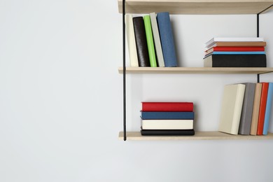 Photo of Shelves with many hardcover books on white wall. Space for text