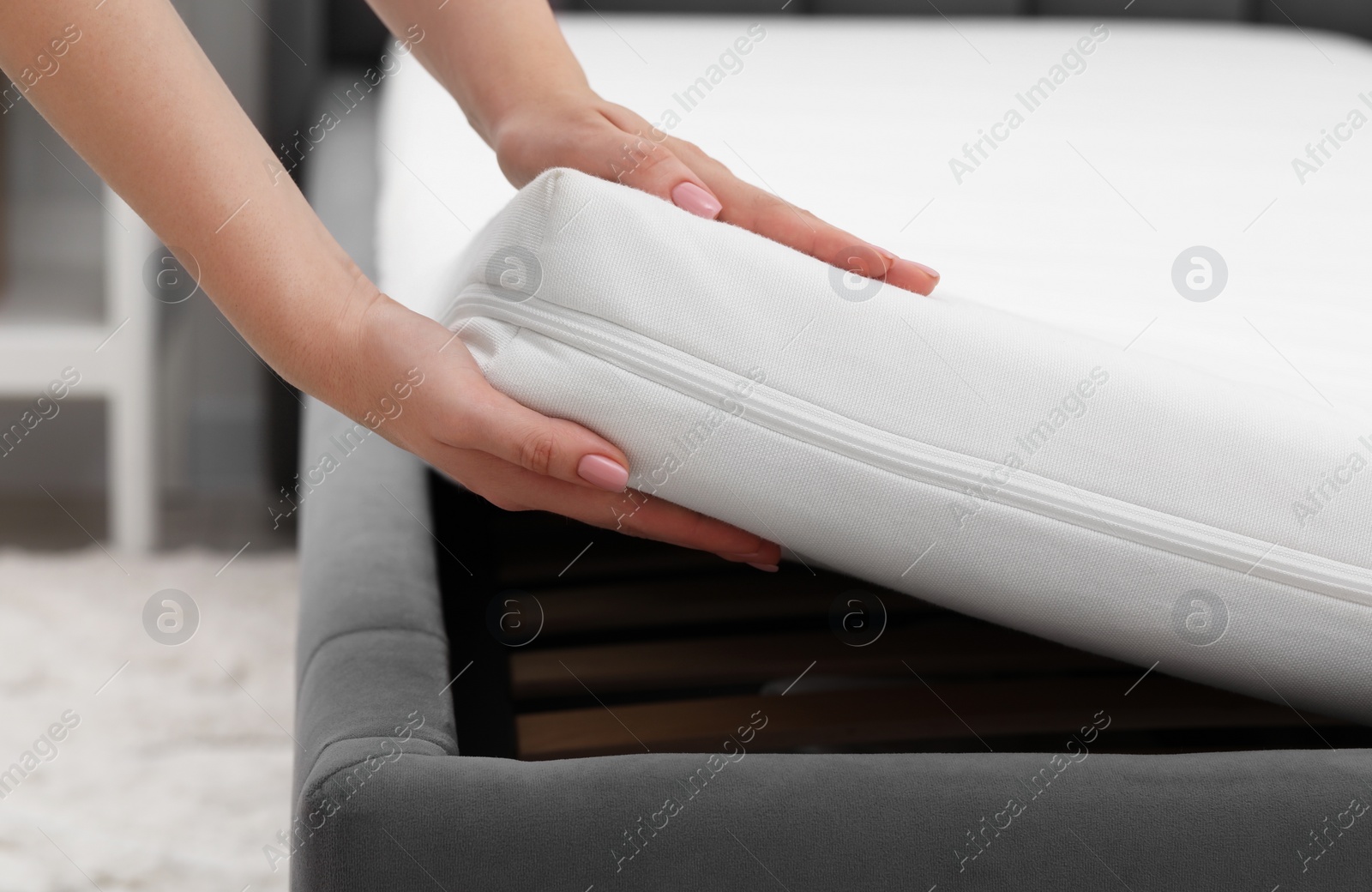 Photo of Woman putting new soft mattress on bed indoors, closeup