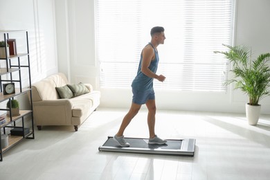 Photo of Sporty man training on walking treadmill at home