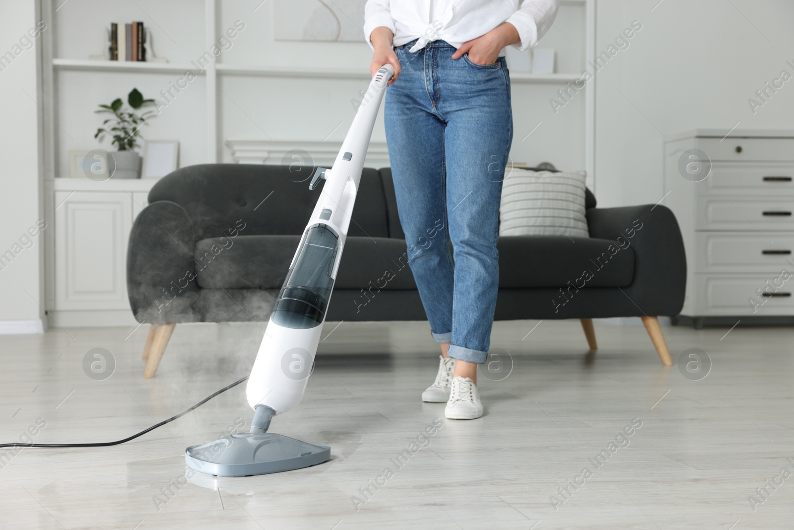 Photo of Woman cleaning floor with steam mop at home, closeup