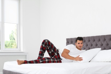 Young man lying on bed with soft pillows at home