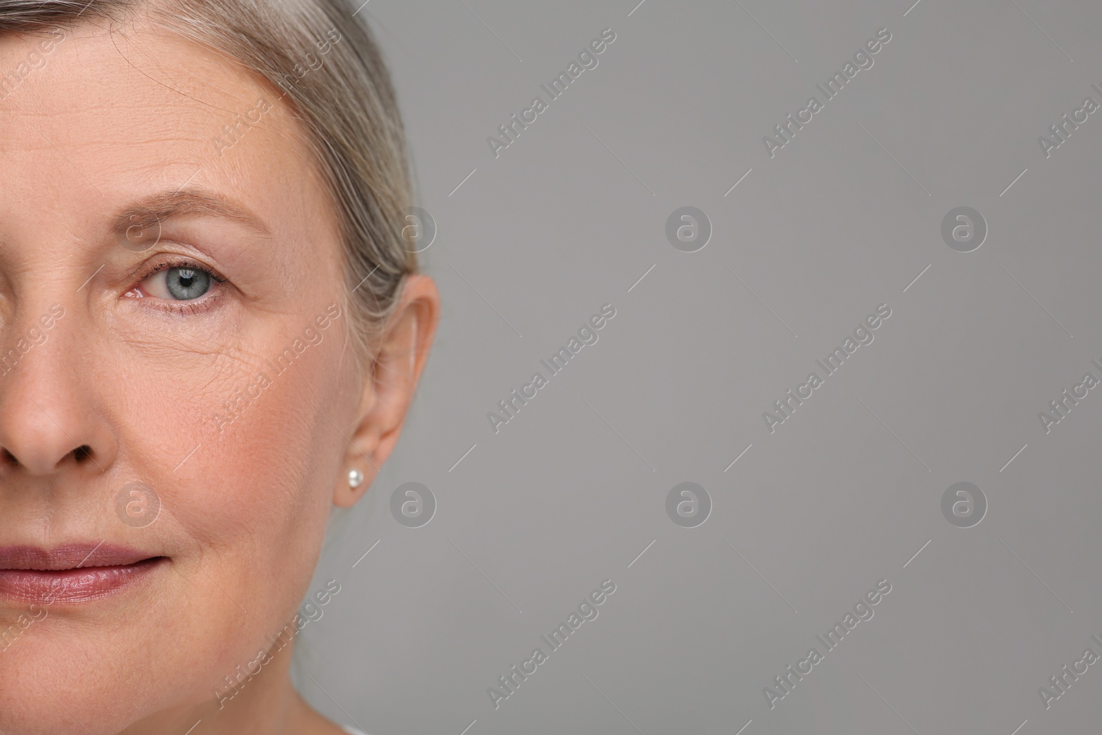 Photo of Senior woman with aging skin on grey background, closeup and space for text. Rejuvenation treatment