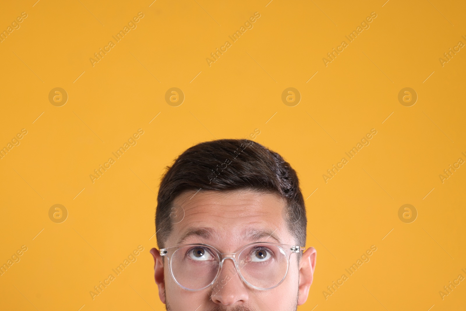 Photo of Man in stylish glasses on yellow background, closeup