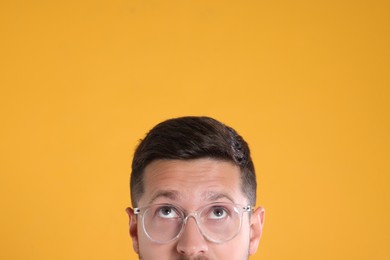 Photo of Man in stylish glasses on yellow background, closeup