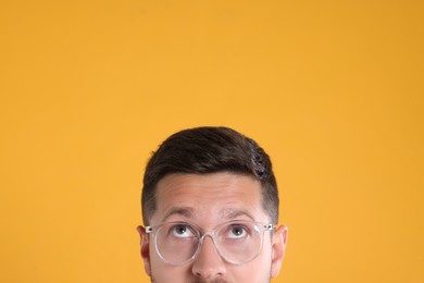 Man in stylish glasses on yellow background, closeup