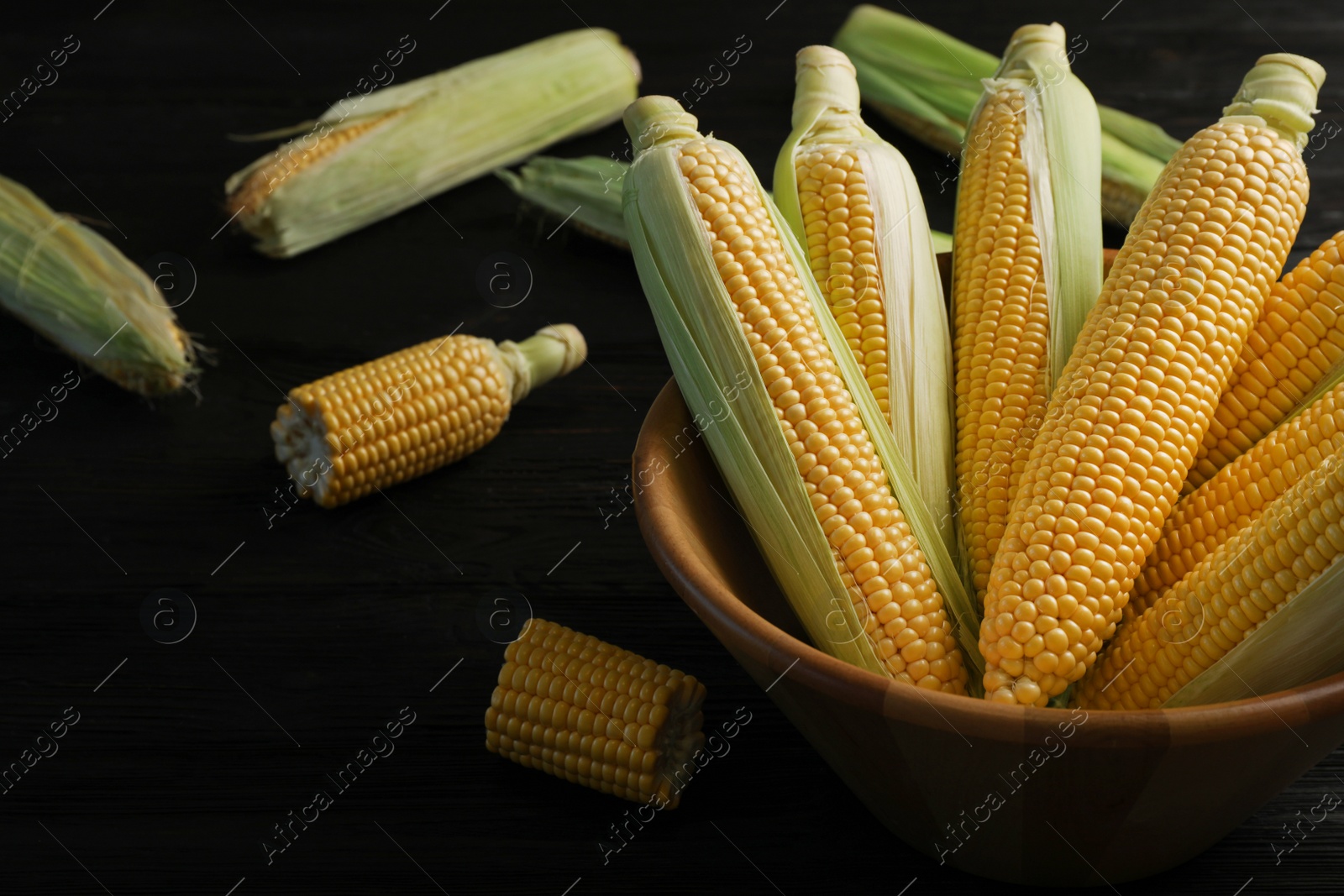 Photo of Bowl with tasty sweet corn cobs on table, closeup