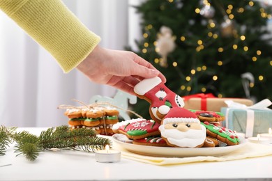 Woman with decorated Christmas cookie at table, closeup