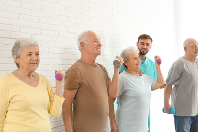 Elderly people training with dumbbells in hospital gym. Senior patients care