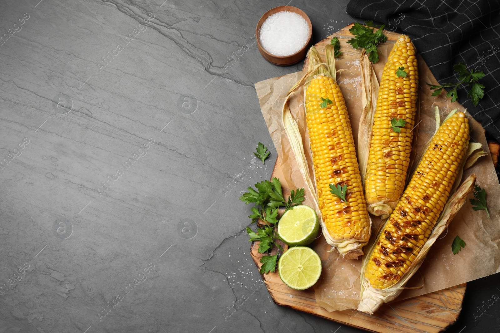 Photo of Tasty grilled corn on black table, flat lay. Space for text