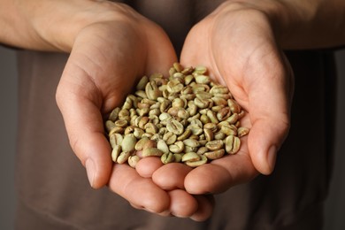 Photo of Woman holding pile of green coffee beans, closeup