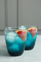 Delicious cocktails with grapefruit and ice balls on grey table, space for text