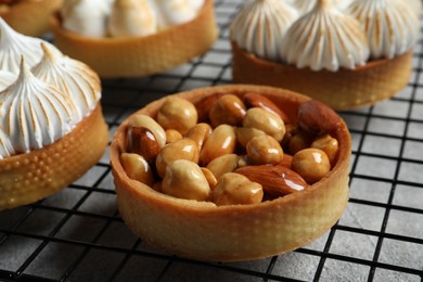 Photo of Many different tartlets on cooling tray, closeup. Tasty dessert