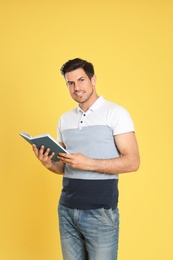 Photo of Handsome man reading book on color background