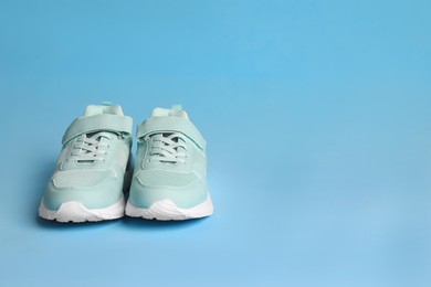 Pair of stylish sneakers on light blue background. Space for text