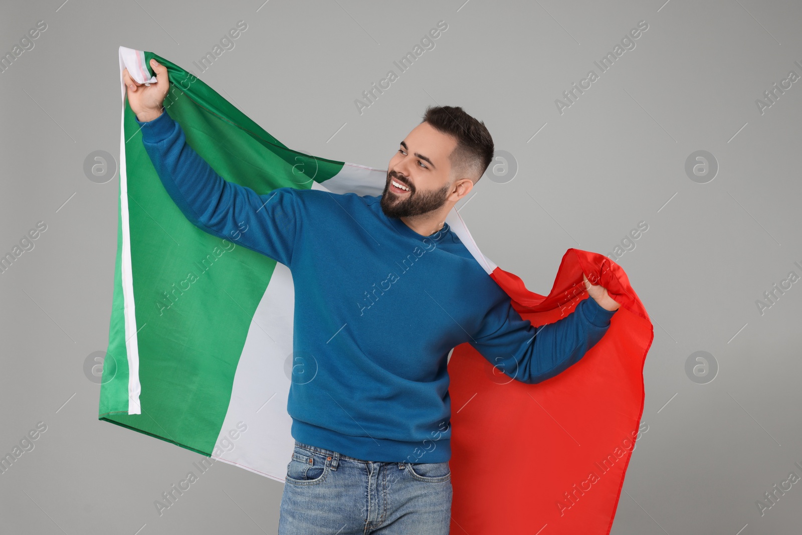 Photo of Young man holding flag of Italy on light grey background