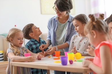 Photo of Young woman playing with little children indoors