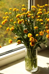 Photo of Beautiful ranunculus flowers in vase on windowsill indoors