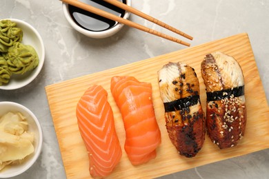 Photo of Delicious nigiri sushi, soy sauce, wasabi, ginger and chopsticks on light grey marble table, flat lay