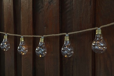 Photo of Garland of lamp bulbs hanging on wooden wall. String lights