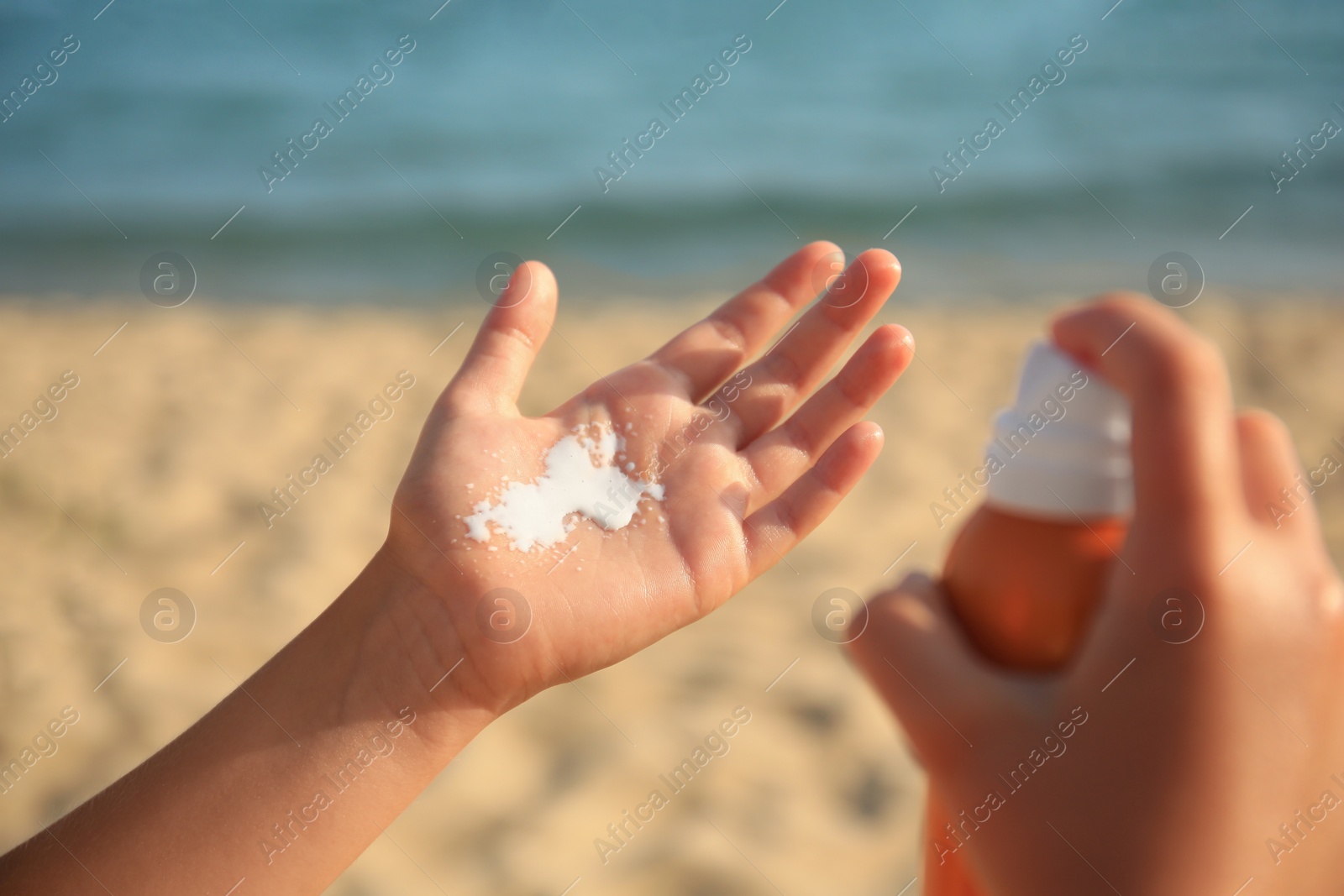 Photo of Child applying sunscreen near sea, closeup. Sun protection care