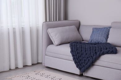 Photo of Living room interior with knitted merino wool blanket on sofa