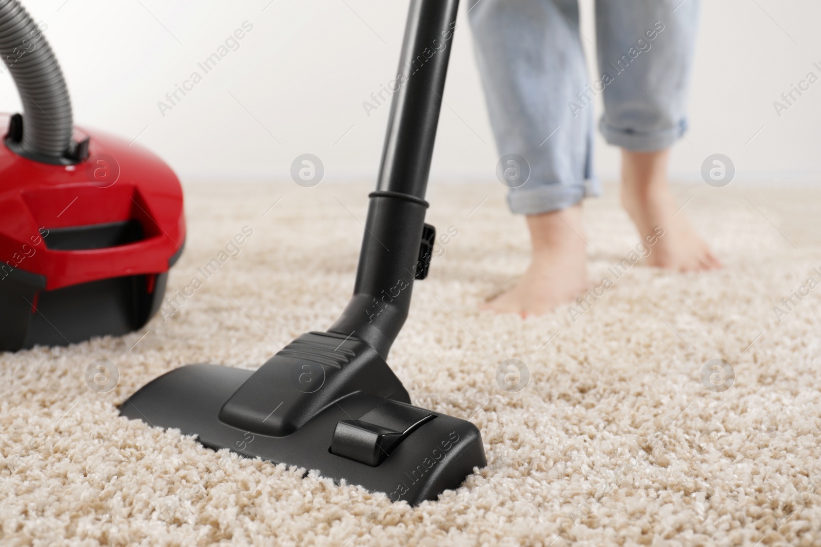 Photo of Woman cleaning carpet with vacuum cleaner at home, closeup