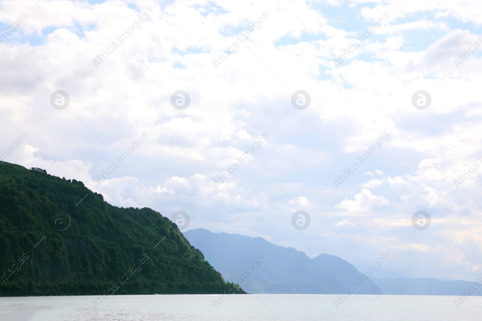 Photo of Picturesque view of beautiful sea and mountains under sky with clouds