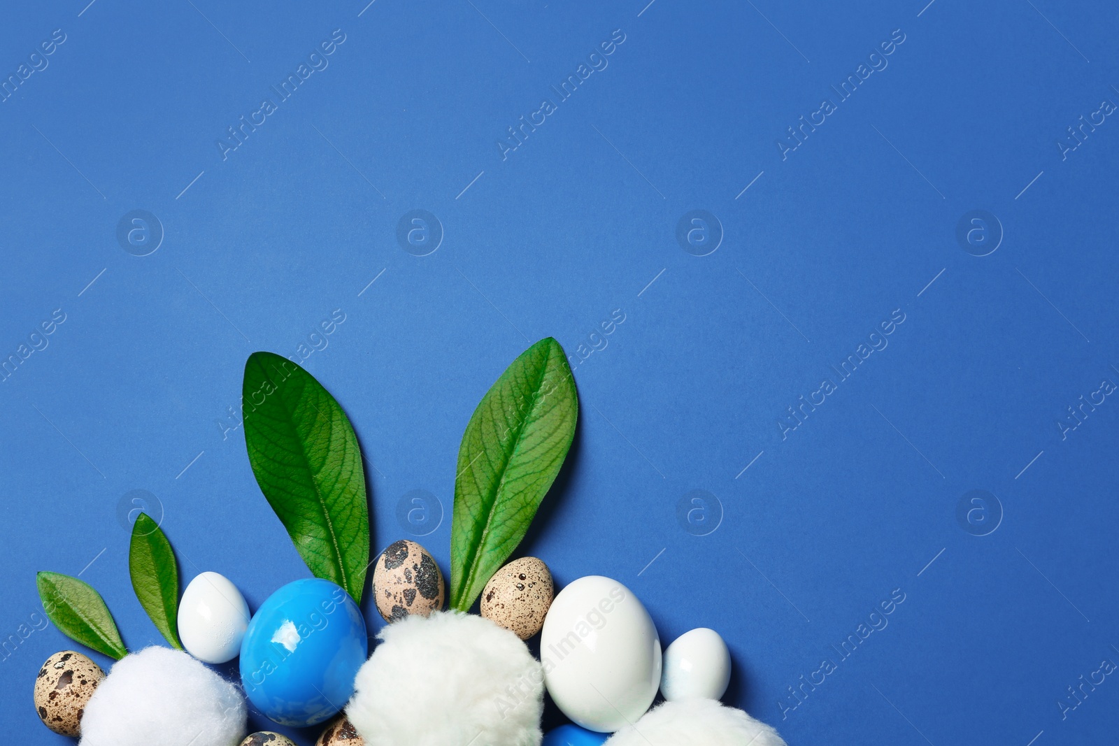 Photo of Creative flat lay composition with Easter bunny ears made of green leaves and eggs on color background, space for text