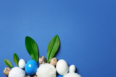 Creative flat lay composition with Easter bunny ears made of green leaves and eggs on color background, space for text