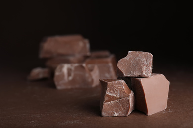 Pieces of milk chocolate on brown table