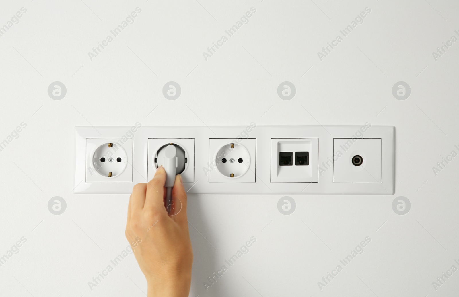 Photo of Woman putting plug into socket indoors, closeup