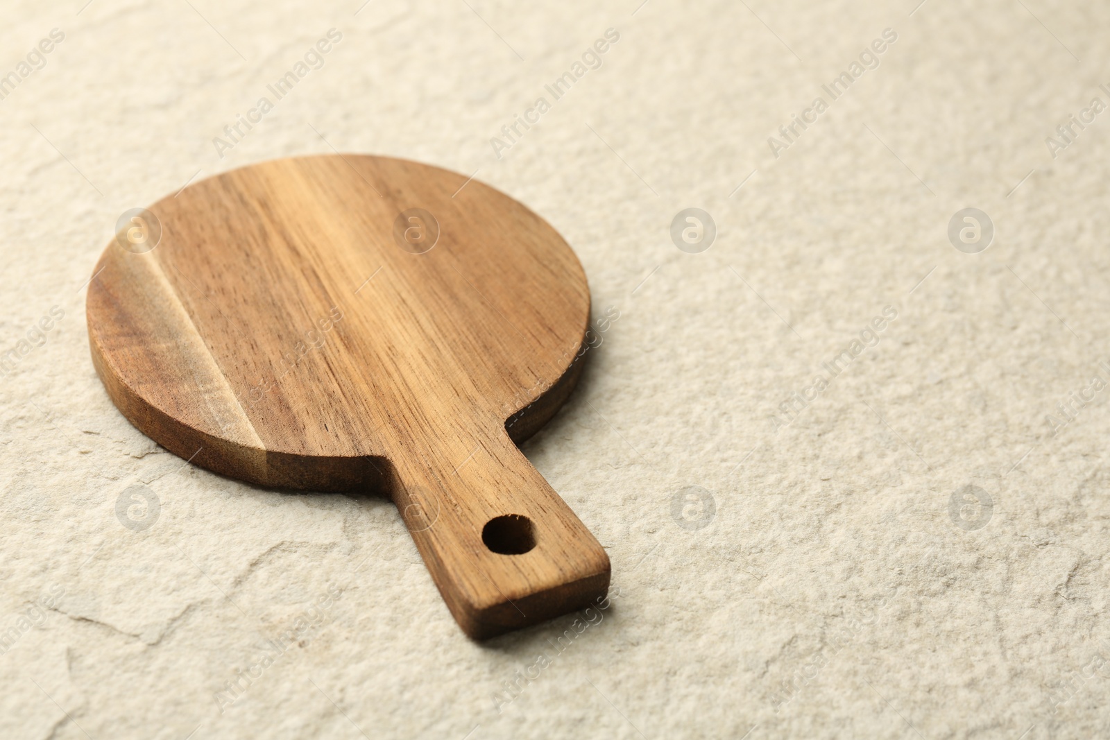 Photo of Wooden cutting board on beige table, space for text