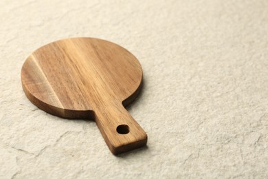 Photo of Wooden cutting board on beige table, space for text