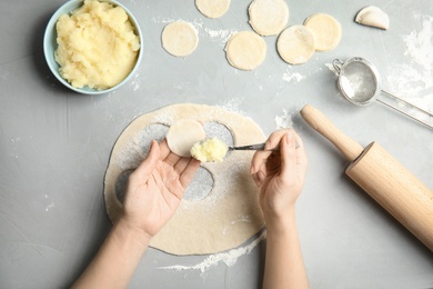 Woman cooking delicious dumplings over grey table, top view