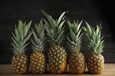 Photo of Fresh ripe juicy pineapples on wooden table