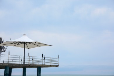Photo of Beautiful view of pier with beach umbrellas against sky. Space for text