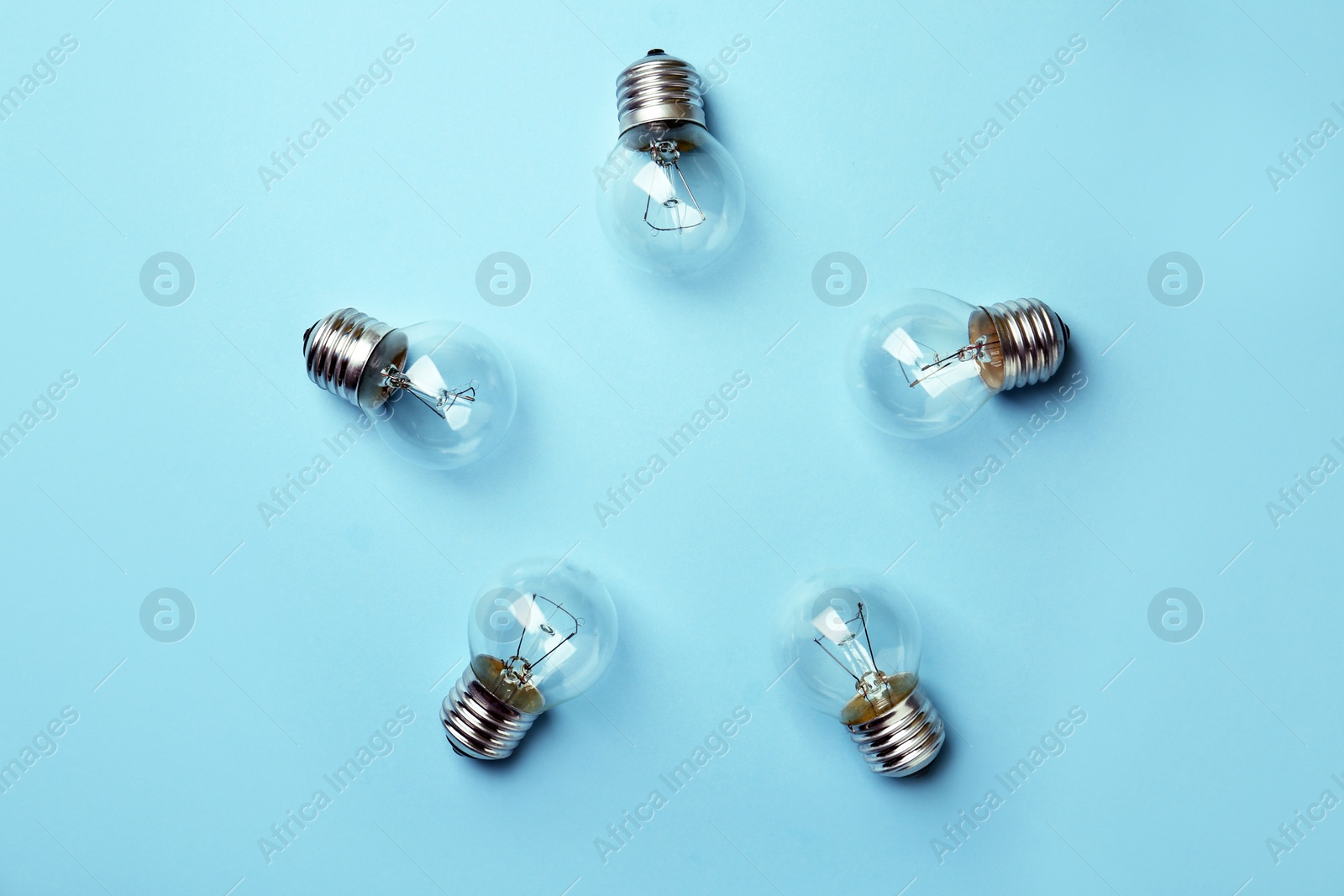 Photo of New incandescent lamp bulbs on light blue background, top view