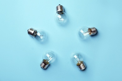 Photo of New incandescent lamp bulbs on light blue background, top view