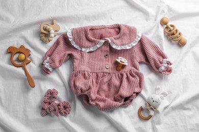 Photo of Flat lay composition with cute baby clothes and accessories on white bedsheet