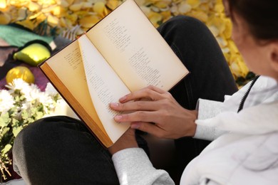 Photo of Woman reading book outdoors on autumn day, above view
