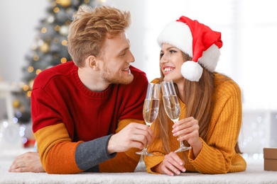 Happy young couple with glasses of champagne at home. Christmas celebration