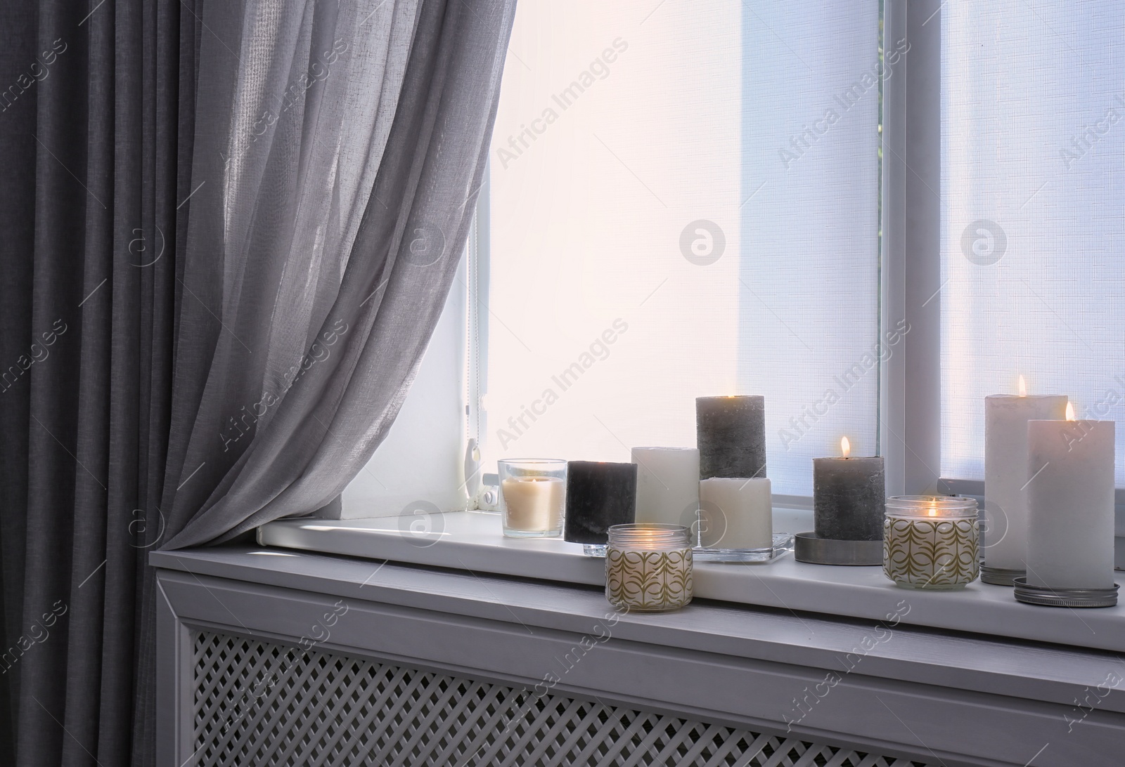 Photo of Burning candles on window sill in room