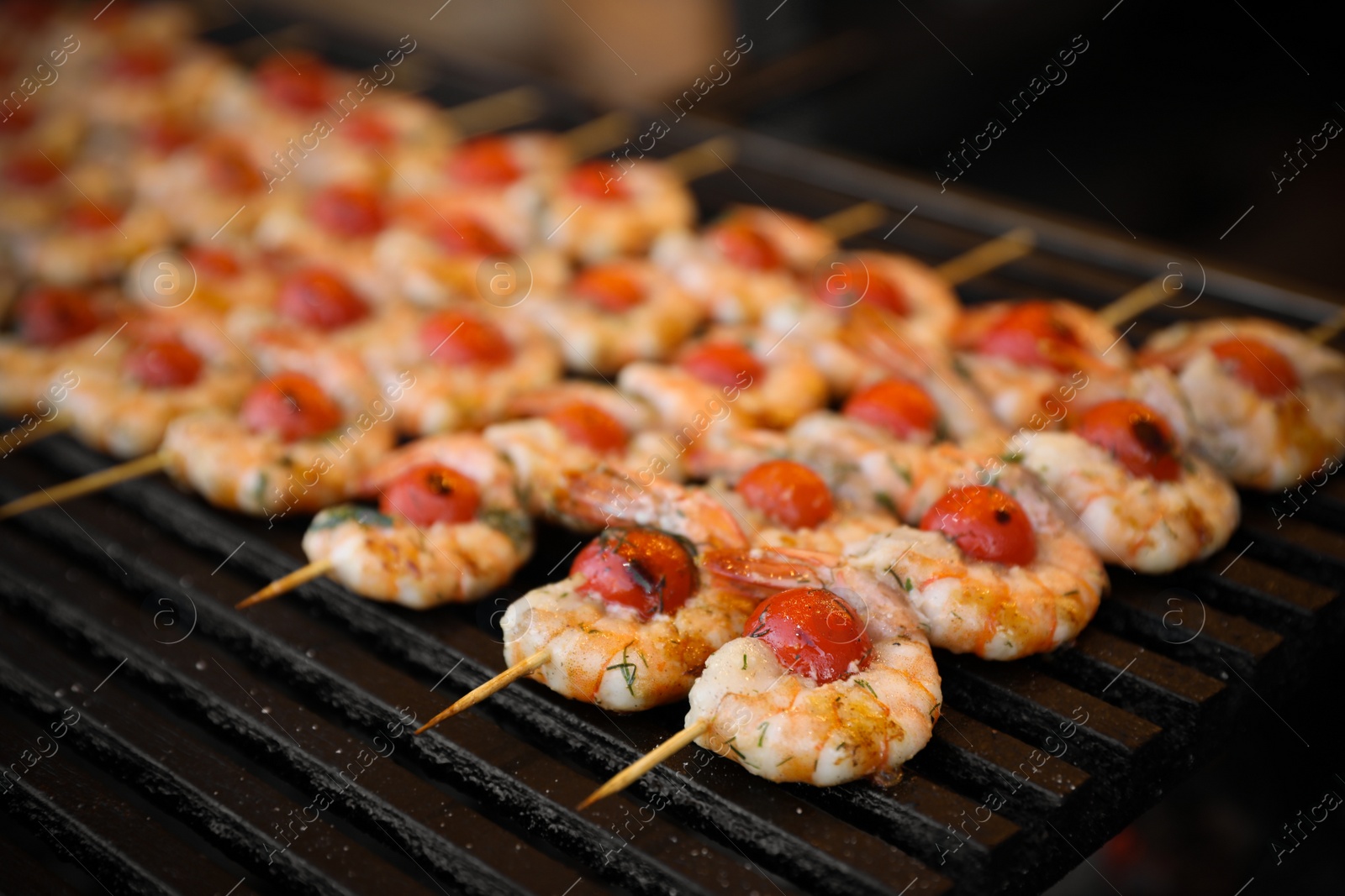 Photo of Delicious fresh shrimp skewers with cherry tomatoes on grill, closeup