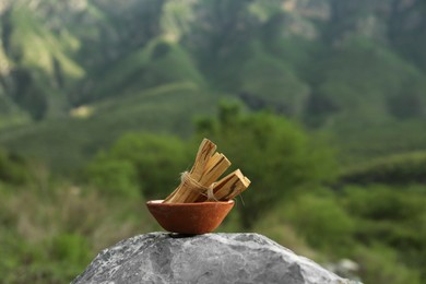 Photo of Many palo santo sticks on stone surface outdoors