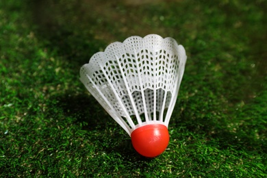 Photo of Plastic shuttlecock on artificial grass, closeup. Badminton equipment