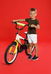 Cute little boy with bicycle on red background