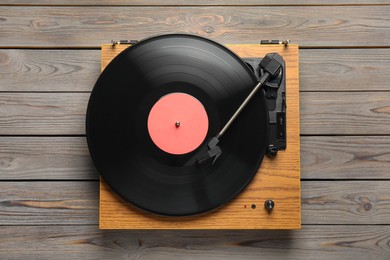 Turntable with vinyl record on grey wooden background, top view