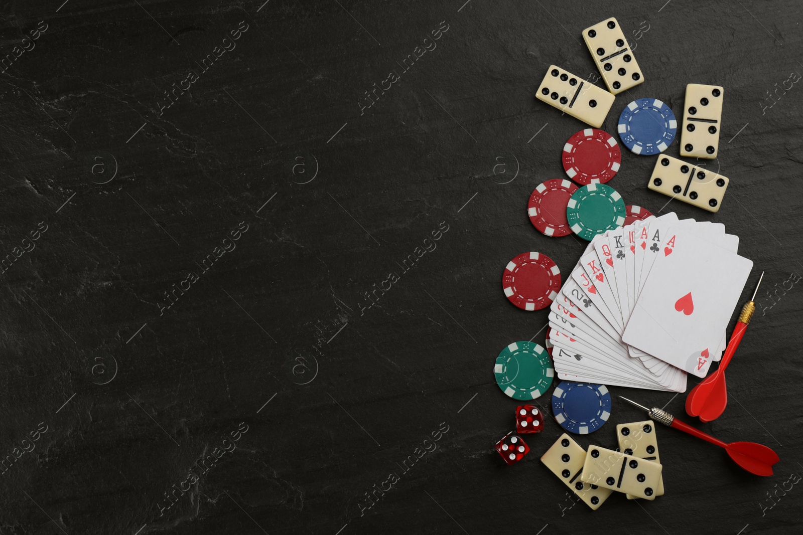 Photo of Elements of different board games on black slate table, flat lay. Space for text